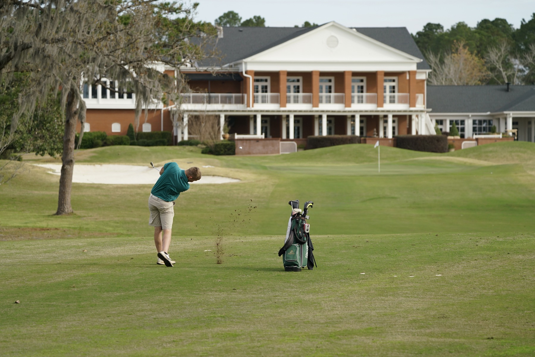 Golfer hitting the ball behind the club house at Forest Lakes Golf Club.